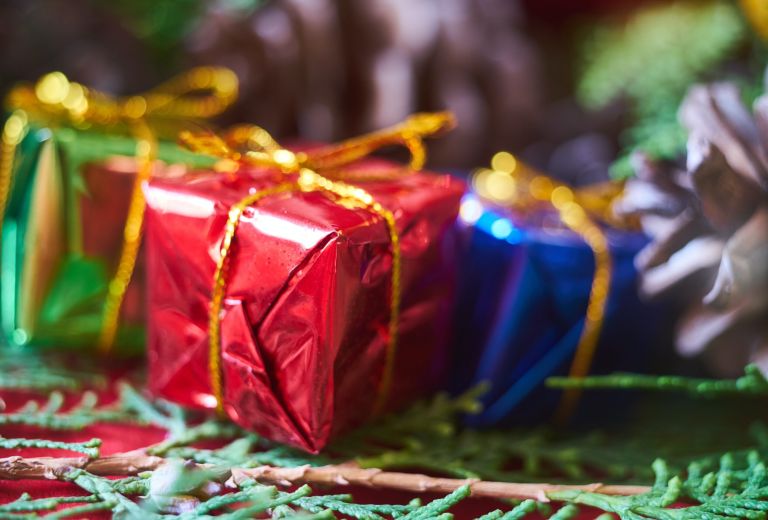 Foto van kleine ingepakte cadeautjes met een gouden strip in foliepapier in de kleuren groen, rood en blauw.