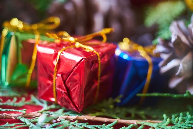 Foto van kleine ingepakte cadeautjes met een gouden strip in foliepapier in de kleuren groen, rood en blauw.
