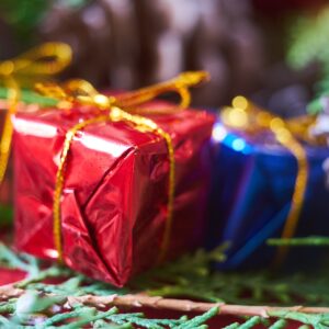 Foto van kleine ingepakte cadeautjes met een gouden strip in foliepapier in de kleuren groen, rood en blauw.